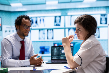 Fototapeta premium Medical specialist showing x ray diagnostic report and blood test analysis to a patient at consultation in cabinet, providing advice and treatment on health insurance. Scan medical results.