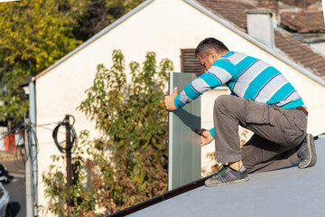 Roofer assembles sheet metal on the roof. A worker  repairing the roof of a home. Roofing