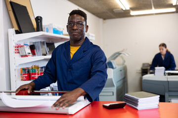 Fototapeta premium Serious print shop worker cuts paper on a professional cutter