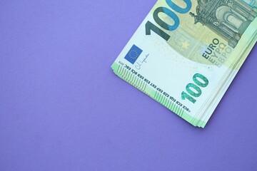 Big amount of one hundred euro money bills on lilac background