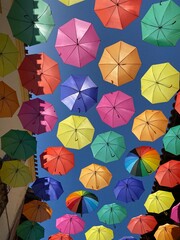 Naklejka premium Bright and colourful umbrellas hanging above buildings