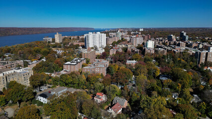 Fototapeta premium This location in the Bronx offers stunning views of lush greenery, a picturesque lake, and urban structures. Framed by the river, it showcases iconic bridges and the New York City skyline in the dista