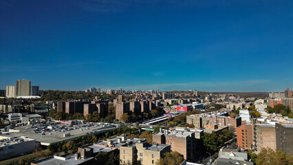 Naklejka premium This location in the Bronx offers stunning views of lush greenery, a picturesque lake, and urban structures. Framed by the river, it showcases iconic bridges and the New York City skyline in the dista