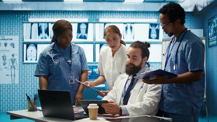 Healthcare professionals examine human anatomy scans to develop treatment plans, teamwork and expertise in radiology. Medical specialists work with analytics at private clinic. Camera B.