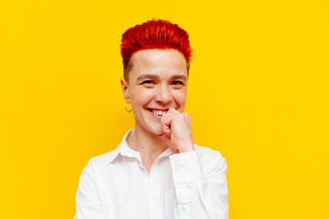 young short-haired red-haired girl smiling and looking at the camera on a yellow isolated...