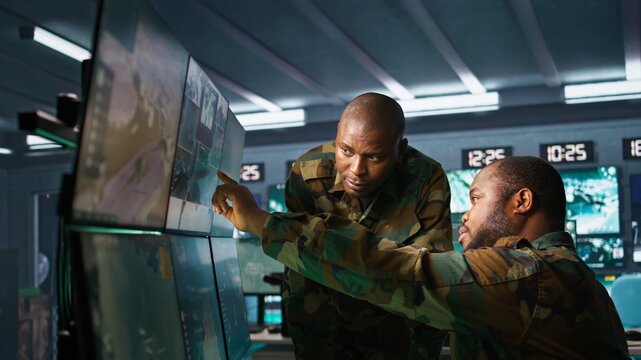 Team of soldiers looking at screens in command center housing operational missile defense system designed to intercept ballistic rockets. Tracking equipment operators using radar systems, camera B