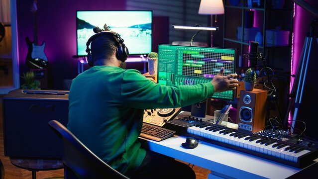 Skilled audio technician editing recorded tracks from an usb stick, using raw files to apply mix and master techniques. Artist producing music, adjusting volume levels on digital software. Camera B.