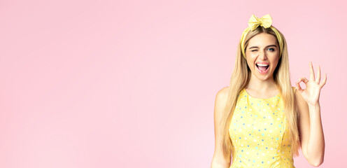 I'm Fine. Smiling blonde woman showing ok sign, winking and looking at camera isolated over pink wall, copyspace