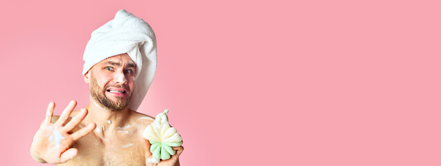 Millennial guy takes a shower and closes with hand on pink background, copy space