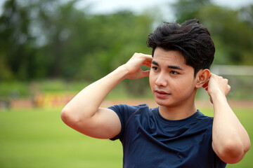 Young man adjusting his hair after an outdoor workout on a track, looking relaxed and casual expression, close up with copy space