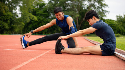 Two young men engaged in post-workout stretching on a track, flexibility and recovery exercises