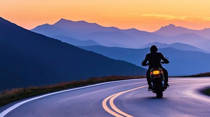 A motorcyclist riding along a winding road against a sunset backdrop.