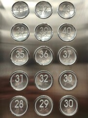 an elevator panel with numbered buttons with braille markings on each button.