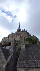 A majestic castle stands atop a hill, with a cloudy sky providing a dramatic backdrop. The...