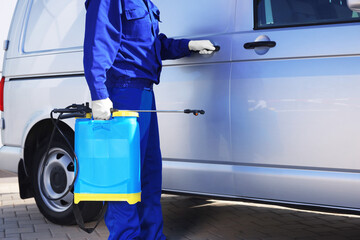 Pest control worker with spray tank near gray minibus outdoors, closeup