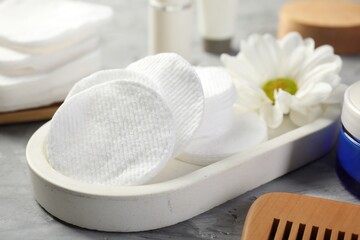 Clean cotton pads and flower on grey table, closeup
