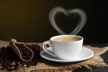 Fresh aromatic coffee and beans on table, space for text. Steam in shape of heart over cup