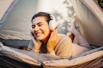 Young woman listening to music or audio book in tent in backyard	