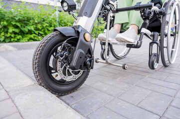 A faceless woman in a wheelchair with an assistive device for manual control. Electric handbike. 