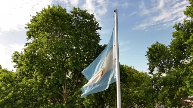 bandera argentina flameando sobre sol, cielo azul	