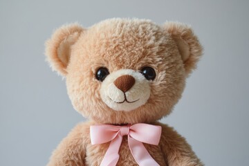 Fototapeta premium Brown teddy bear wearing a pink bow tie smiling on a gray background