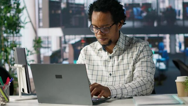 African american general manager reviews business forecasts and plans on his laptop at office desk, strategy planning. Data analyst focuses on company objectives and resource allocation. Camera A.