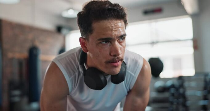 Man, headphones and tired in gym for fitness, exercise and break with challenge, cardio and workout. Athlete, training and breathing in sports club for fatigue, recovery and health with muscle growth