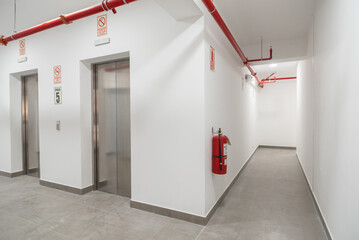 lobby con ascensor en edificio de oficinas con sistema contra incendios en el techo 