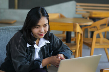 Fototapeta premium pretty asian woman using laptop in cafe doing virtual online meeting with client and watching course webinar with smile face