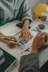 engineers are sitting discussing a construction plan that needs to be revised to make the structure...