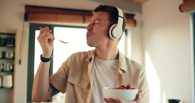 Happy man, headphones and dancing with salad bowl for music, breakfast or healthy meal at home. Young, male person or nutritionist feeling good with snack and organic food for morning in kitchen