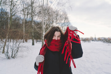 A smiling woman with a red scarf enjoys a snowy winter day in a serene forest setting beneath a...