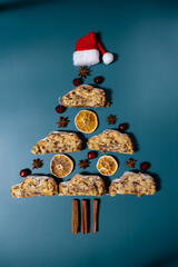 Christmas tree made of Slices of Homemade traditional cake pie with marzipan nuts and dried fruits pastry dessert stollen. Winter holidays season atmosphere. Creative minimalistic greeting card