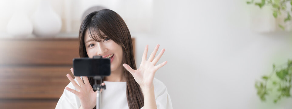 撮影する動画配信者のイメージ　かわいい若い女性がカメラに向けてバイバイと手を振るバナー