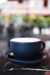 A delightful cappuccino served in a dark blue cup resting elegantly on a charming table