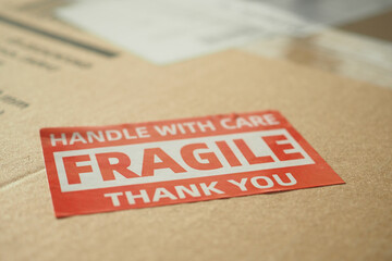 A cardboard box marked with a caution label for fragile goods handling during shipping