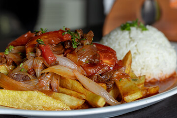 Un plato de un jugoso lomo saltado, acompañado con su porción de arroz blanco, en plato blanco