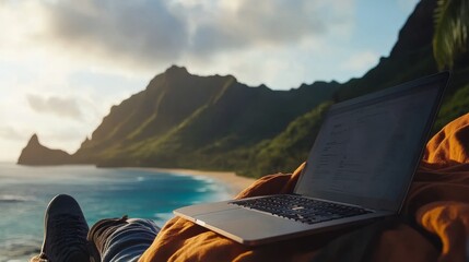 A peaceful beach scene featuring a laptop resting on a blanket, surrounded by mountains and ocean, perfect for remote work and relaxation.