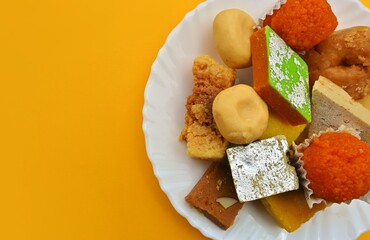 Indian traditional sweets, Diwali sweets, isolated on yellow background