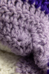 close-up of crochet stitches of a lilac purple blanket with white and royal purple, crocheted or knitted, reminds you of grandma's house, cozy and warm background