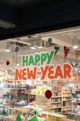 The vibrant storefront greets visitors with cheerful Happy New Year decorations, creating a warm and inviting atmosphere perfect for holiday shopping and celebration. 