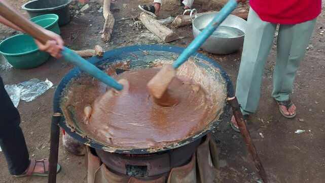 Men make traditional Indonesian food jenang stirred strongly in rhythm. Jenang is a typical Javanese food made from glutinous rice flour, brown sugar and coconut milk which produces a savory and sweet
