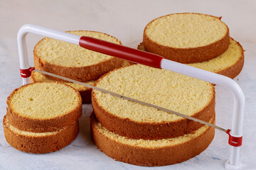 Baker cutting the top of cake with a serrated leveler cake. Making a layer cake.