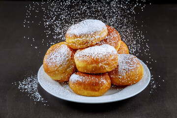 Homemade donuts in white plate powdering with sugar.
