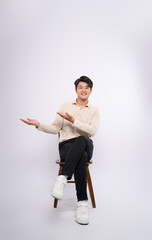 Full body image of a young businessman sitting in a chair and posing on a white background