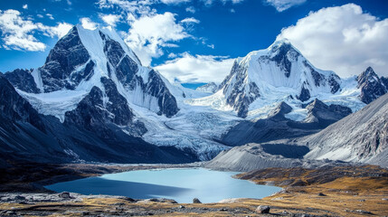 Fototapeta premium A snowy mountain range with tall, icy peaks sits in a wild landscape. There's a big glacier and a lake formed by the melting ice.