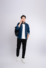 Full body image of young Asian male student using phone and posing on white background