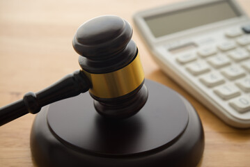 Gavel hammer judge and white calculator on wooden table background. Tax law, financial law or...