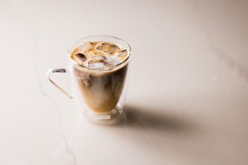 An artisanal glass mug of coffee mixed with milk