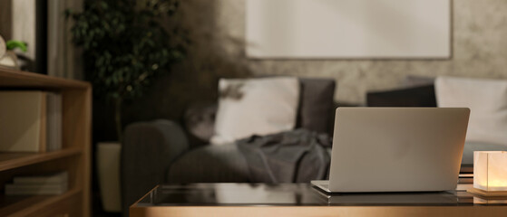 A close-up of a laptop on a coffee table in a contemporary grey living room at night.